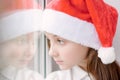 Adorable little girl in Santa hat near the window Royalty Free Stock Photo