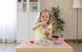 Adorable little girl sculpts cupcakes from kinetic sand. Royalty Free Stock Photo