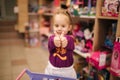 Adorable little girl shopping for toys. Cute female in toy store. Happy young girl selecting toy