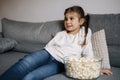 Adorable little girl watching TV at home and laughs. Cute girl eating popcorn. Holiday mood Royalty Free Stock Photo