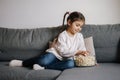 Adorable little girl sits on sofa and watching TV at home. Cute girl eating popcorn. Holiday mood Royalty Free Stock Photo