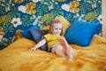 Adorable little girl sitting on bed in nicely decorated bedroom Royalty Free Stock Photo