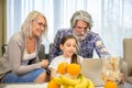 Adorable little girl sitting in front of laptop with smiling senior grandparents Royalty Free Stock Photo