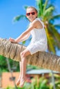 Adorable little girl sitting on palm tree during summer vacation on white beach Royalty Free Stock Photo