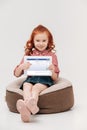 adorable little girl smiling at camera while holding digital tablet with facebook website on screen