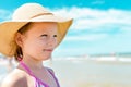 Adorable little girl in a straw hat on the beach during summer