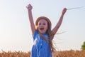 Adorable little girl in a straw hat, blue plaid summer dress in wheat field countryside.Child with long blonde wavy hair Royalty Free Stock Photo