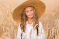 Adorable little girl in a straw hat in wheat field. Child with long blonde wavy hair on countryside landscape with spikelet in Royalty Free Stock Photo