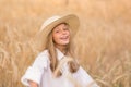 Adorable little girl in a straw hat in wheat field. Child with long blonde wavy hair on countryside landscape with spikelet in Royalty Free Stock Photo