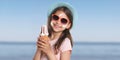 Adorable girl with sun protection cream on face at beach, banner design