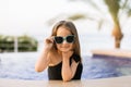 Adorable little girl at swimming pool in a swimsuit and sunglasses having fun during summer vacation Royalty Free Stock Photo