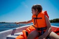Little girl in a swimming vest sits in a motorboat