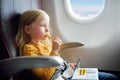 Adorable little girl traveling by an airplane. Child sitting by aircraft window and drawing a picture. Royalty Free Stock Photo