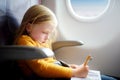 Adorable little girl traveling by an airplane. Child sitting by aircraft window and drawing a picture with felt-tip pens. Royalty Free Stock Photo