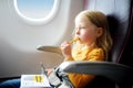 Adorable little girl traveling by an airplane. Child sitting by aircraft window and drawing a picture with felt-tip pens. Royalty Free Stock Photo