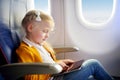 Adorable little girl traveling by an airplane. Child sitting by aircraft window and using a digital tablet during the flight. Trav Royalty Free Stock Photo