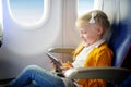 Adorable little girl traveling by an airplane. Child sitting by aircraft window and using a digital tablet during the flight. Trav Royalty Free Stock Photo