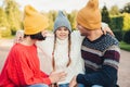 Adorable little girl with two pigtails, wears warm knitted hat and sweater, embrace her affectionate parents, admire beautiful nat