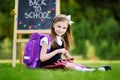 Adorable little girl using computer tablet while sitting on a grass on summer day Royalty Free Stock Photo