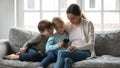 Adorable little girl using telephone applications with brother and mommy. Royalty Free Stock Photo