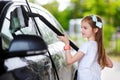 Adorable little girl washing a car on a carwash