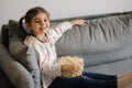 Adorable little girl watching TV at home and laughs. Cute girl eating popcorn. Holiday mood Royalty Free Stock Photo