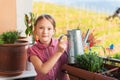 Adorable little girl watering plants on the balcony Royalty Free Stock Photo