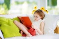 Adorable little girl wearing eyeglasses reading a book in white living room on summer day Royalty Free Stock Photo