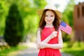 Adorable little girl wearing hat holding american flag outdoors on beautiful summer day Royalty Free Stock Photo