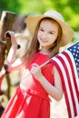 Adorable little girl wearing hat holding american flag outdoors on beautiful summer day Royalty Free Stock Photo