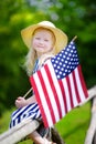 Adorable little girl wearing hat holding american flag outdoors on beautiful summer day Royalty Free Stock Photo