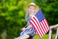 Adorable little girl wearing hat holding american flag outdoors on beautiful summer day Royalty Free Stock Photo