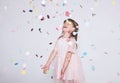 Adorable little girl wearing pink dress in tulle with princess crown on head on white background enjoy confetti surprise Royalty Free Stock Photo