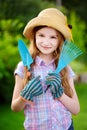 Adorable little girl wearing straw hat holding garden tools Royalty Free Stock Photo