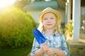 Adorable little girl wearing straw hat holding toy garden tool on sunny summer day. Royalty Free Stock Photo