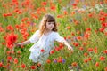 Adorable little girl in white dress playing in poppy flower field. Child picking red poppies. Toddler kid having fun in summer me Royalty Free Stock Photo