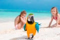 Adorable little girls at beach with colorful parrot