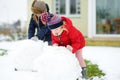 Adorable little girls building a snowman in the backyard. Cute children playing in a snow. Royalty Free Stock Photo