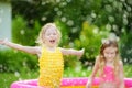 Adorable little girls playing in inflatable baby pool. Happy kids splashing in colorful garden play center on hot summer day. Royalty Free Stock Photo