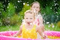 Adorable little girls playing in inflatable baby pool. Happy kids splashing in colorful garden play center on hot summer day. Royalty Free Stock Photo