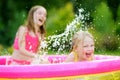 Adorable little girls playing in inflatable baby pool. Happy kids splashing in colorful garden play center on hot summer day. Royalty Free Stock Photo