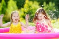 Adorable little girls playing in inflatable baby pool. Happy kids splashing in colorful garden play center on hot summer day. Royalty Free Stock Photo