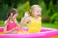 Adorable little girls playing in inflatable baby pool. Happy kids splashing in colorful garden play center on hot summer day. Royalty Free Stock Photo