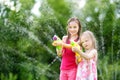 Adorable little girls playing with water guns on hot summer day. Cute children having fun with water outdoors. Royalty Free Stock Photo