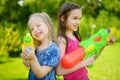 Adorable little girls playing with water guns on hot summer day. Cute children having fun with water outdoors. Royalty Free Stock Photo
