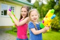 Adorable little girls playing with water guns on hot summer day. Cute children having fun with water outdoors. Royalty Free Stock Photo