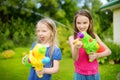 Adorable little girls playing with water guns on hot summer day. Cute children having fun with water outdoors. Royalty Free Stock Photo