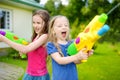 Adorable little girls playing with water guns on hot summer day. Cute children having fun with water outdoors. Royalty Free Stock Photo