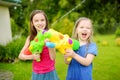 Adorable little girls playing with water guns on hot summer day. Cute children having fun with water outdoors. Royalty Free Stock Photo