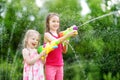 Adorable little girls playing with water guns on hot summer day. Cute children having fun with water outdoors. Royalty Free Stock Photo